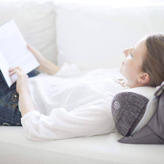 Woman relaxing on couch using Synca Wellness Lumbar Massage Cushion for lower back support and comfort