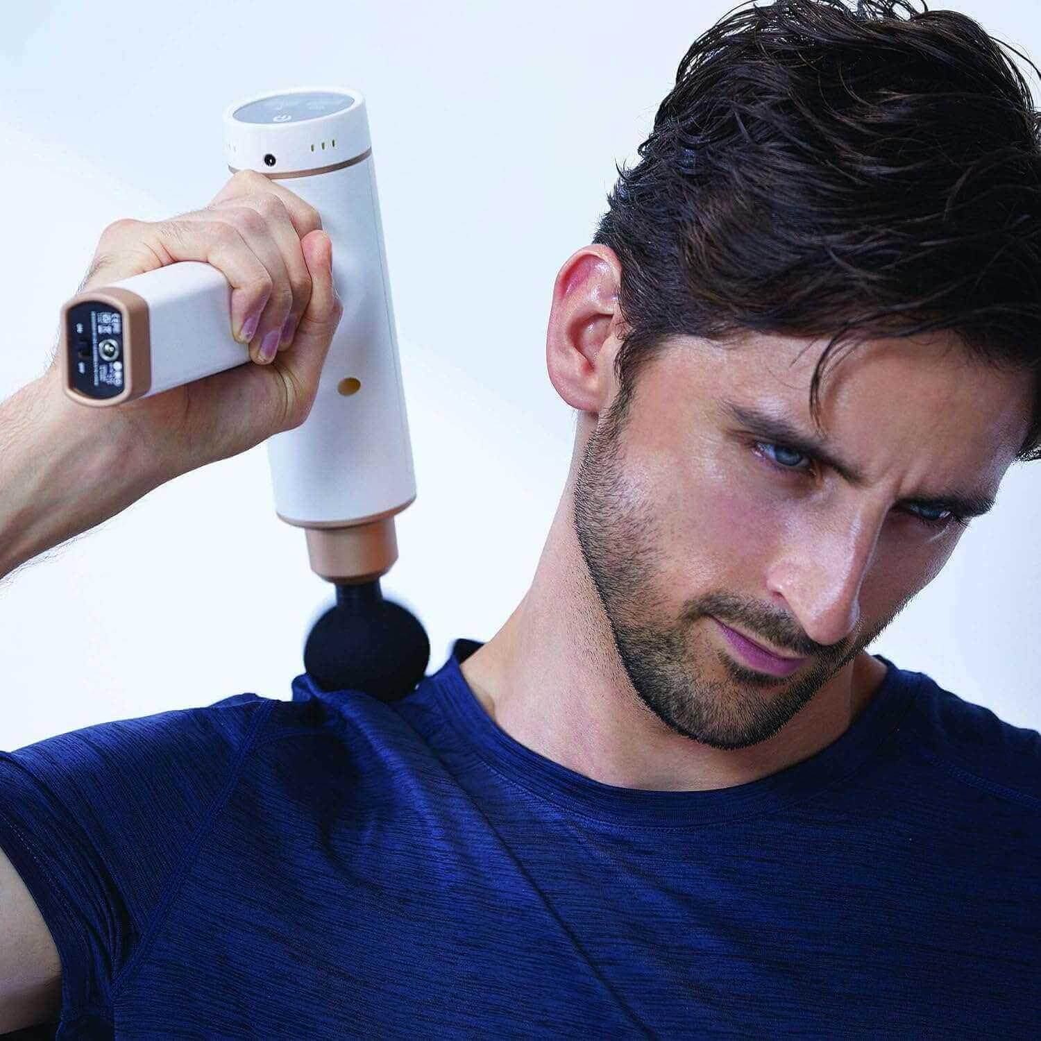 Synca Wellness percussive massage gun in white being used on shoulder by man in blue shirt