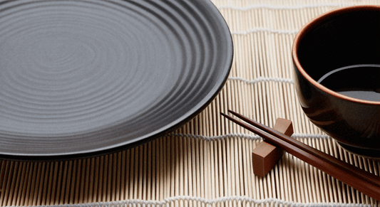 Empty Japanese plate bowl and chopsticks on bamboo mat in a dining scene highlighting Japan’s Leading Massage Chair