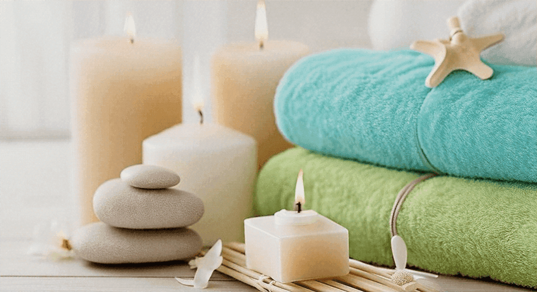 Discover Features for the Perfect Home Spa Experience with turquoise and green rolled towels, stacked stones, candles and a starfish