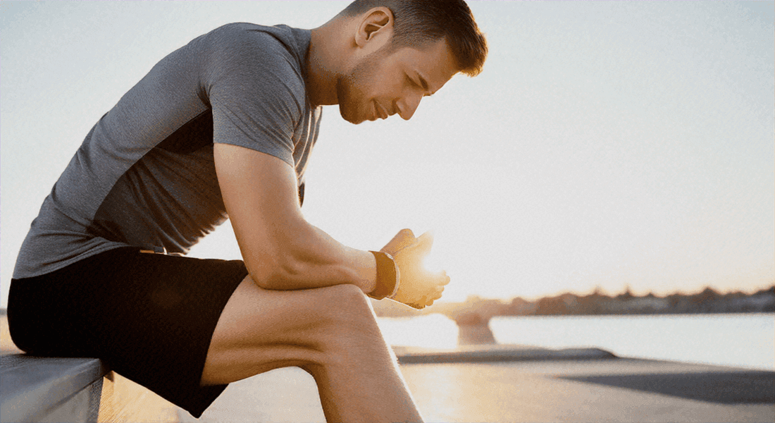 Man sitting and leaning forward to stretch after exercise, wearing a gray short-sleeve shirt and black shorts; Why a Massage Chair is Essential for Daily Fatigue Relief