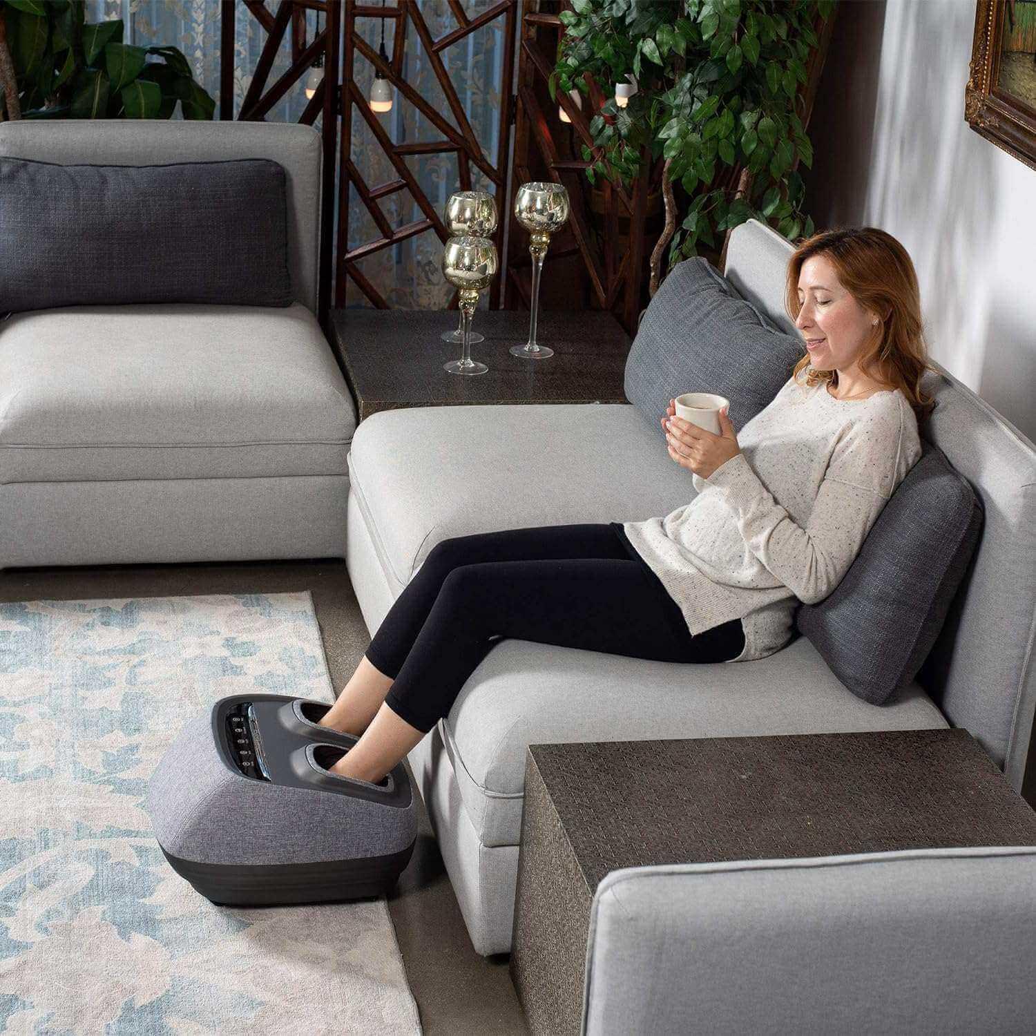 Inner Balance Arch Refresh Foot Massager in gray with woman relaxing on sofa using it