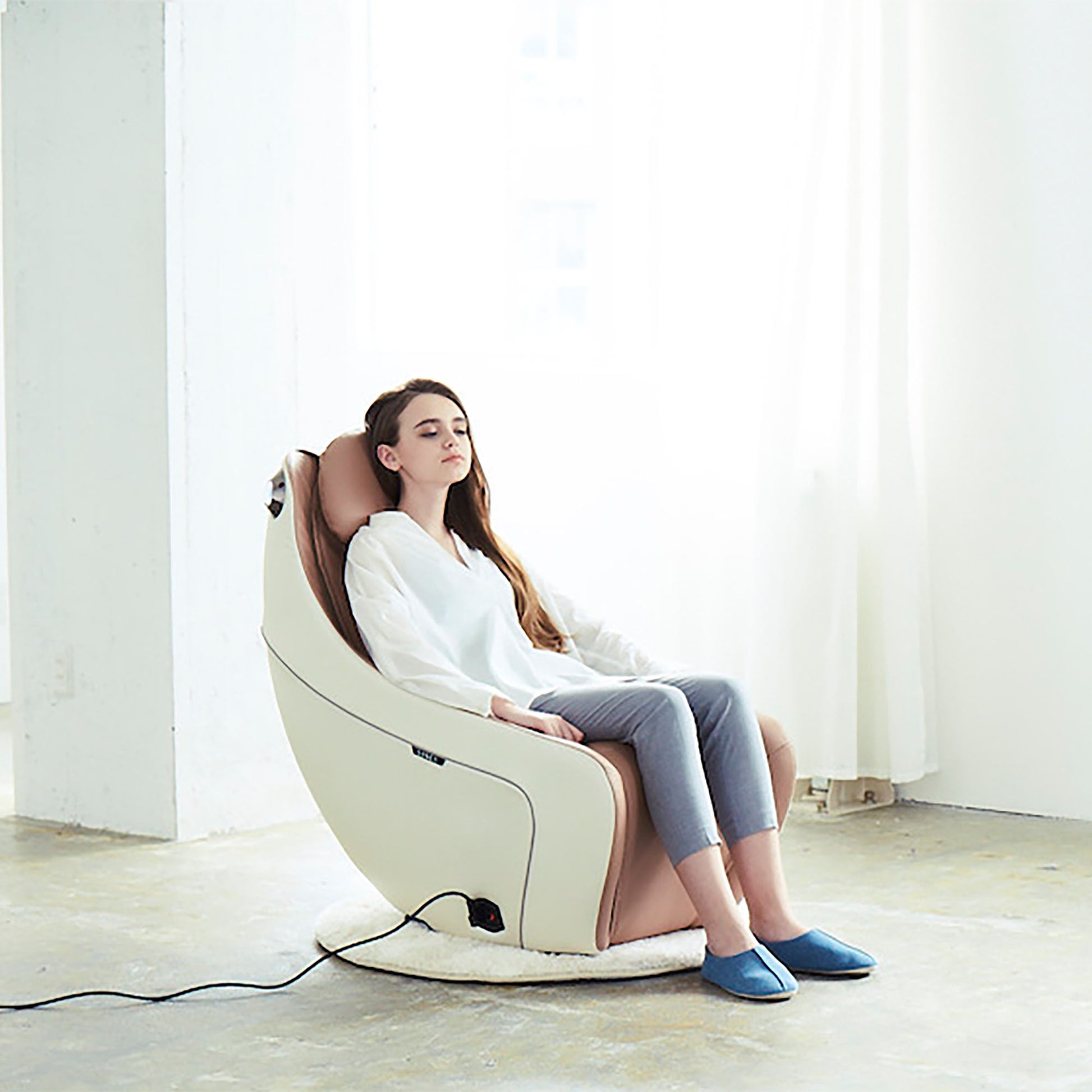 Woman relaxing in Synca Wellness CirC compact Massage Chair in modern white and brown design