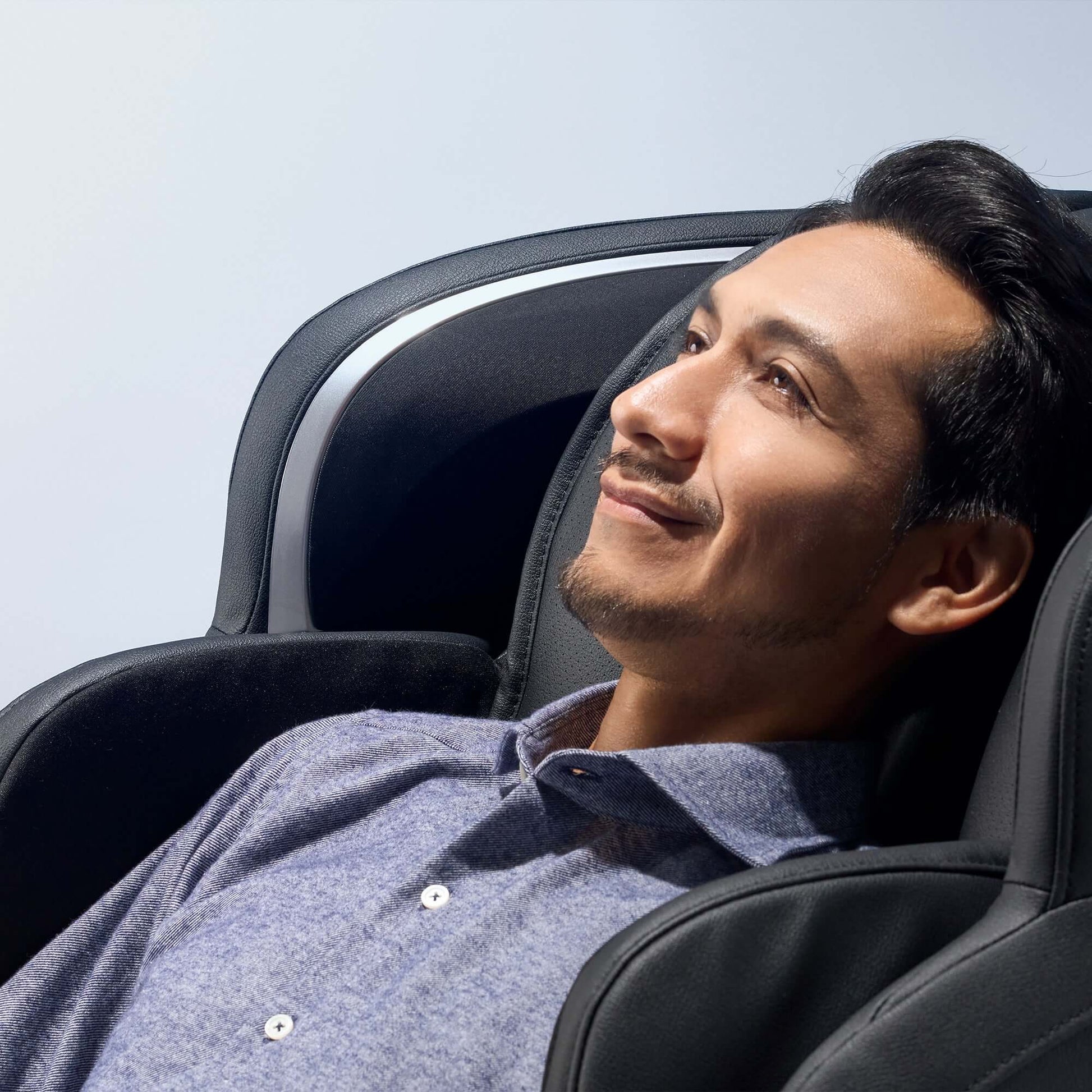 Man relaxing in black Fujiiryoki electric massaging chair with Cyber Relax Ai technology