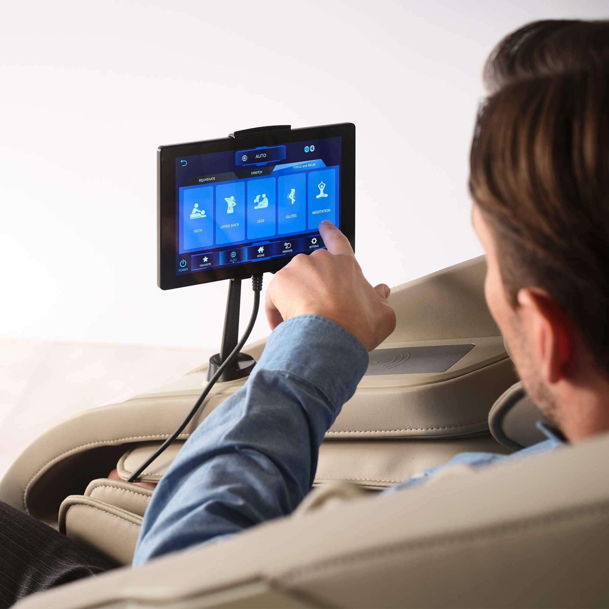 Man using touchscreen remote control of Cyber Relax Elite Massage Chair by Fujiiryoki