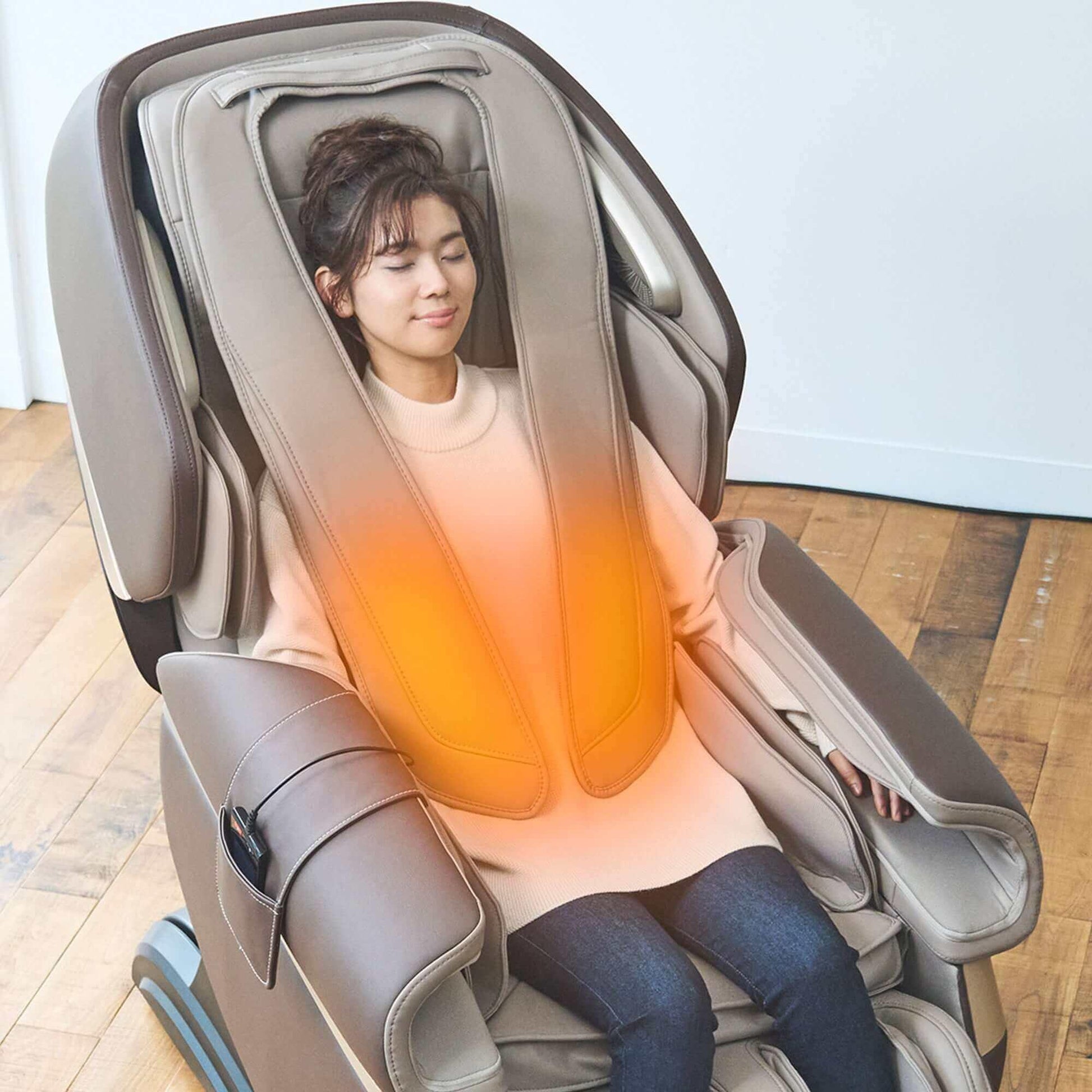 Fujiiryoki Calm Plus electric massaging chair in brown with a woman relaxing while using heated massage feature