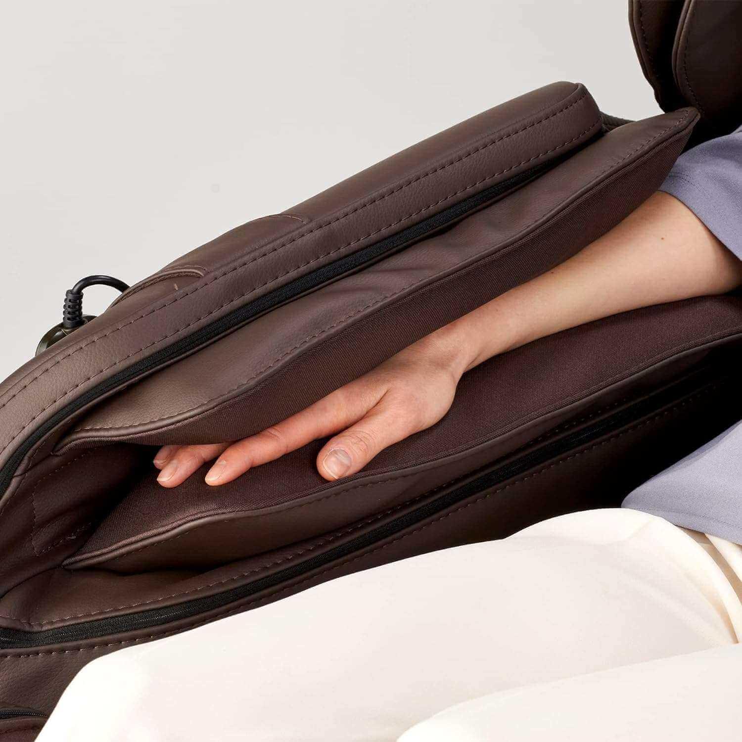 Close-up of a hand inside the brown Synca Wellness Hisho massage chair armrest cushion