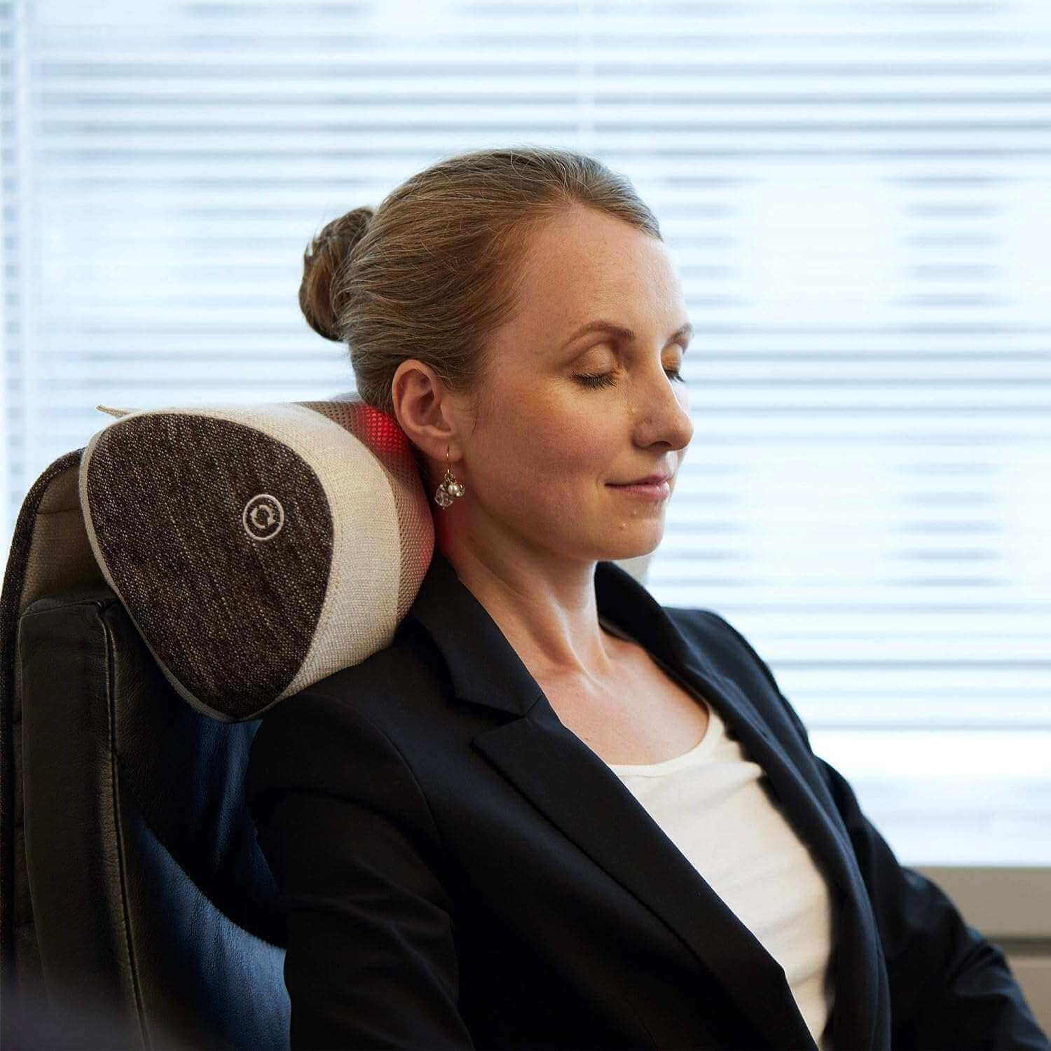 Synca Wellness Lumbar Massage Cushion providing neck and back support for a relaxed woman sitting in a chair
